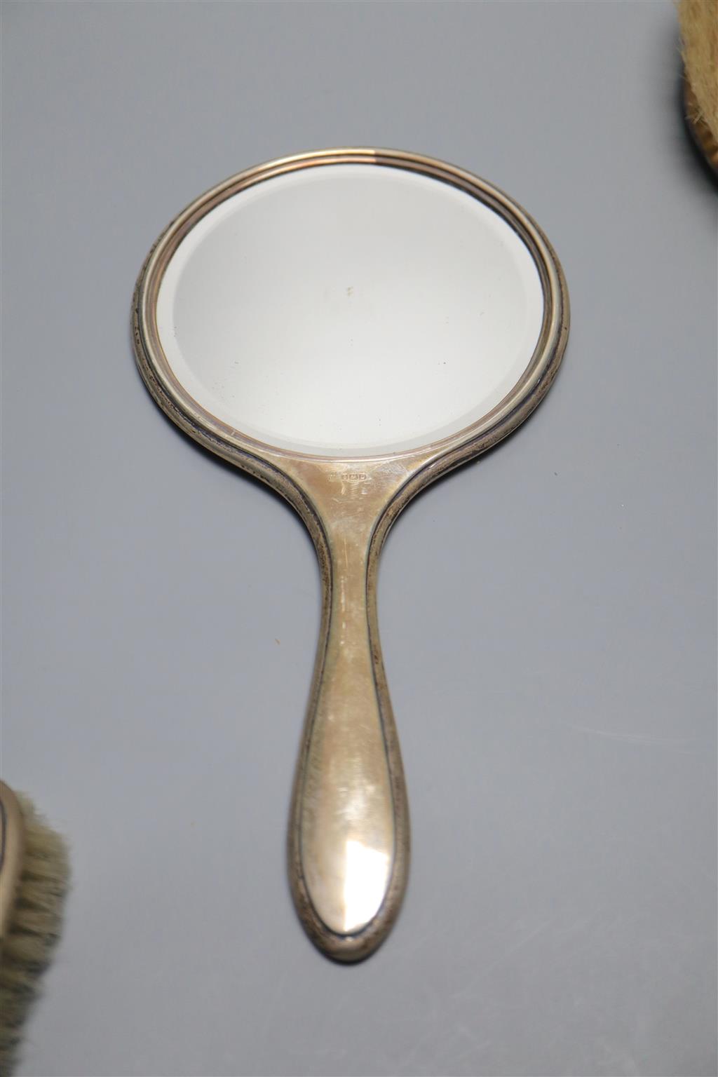 Two late 1920s silver mounted hand mirrors and three silver mounted brushes.